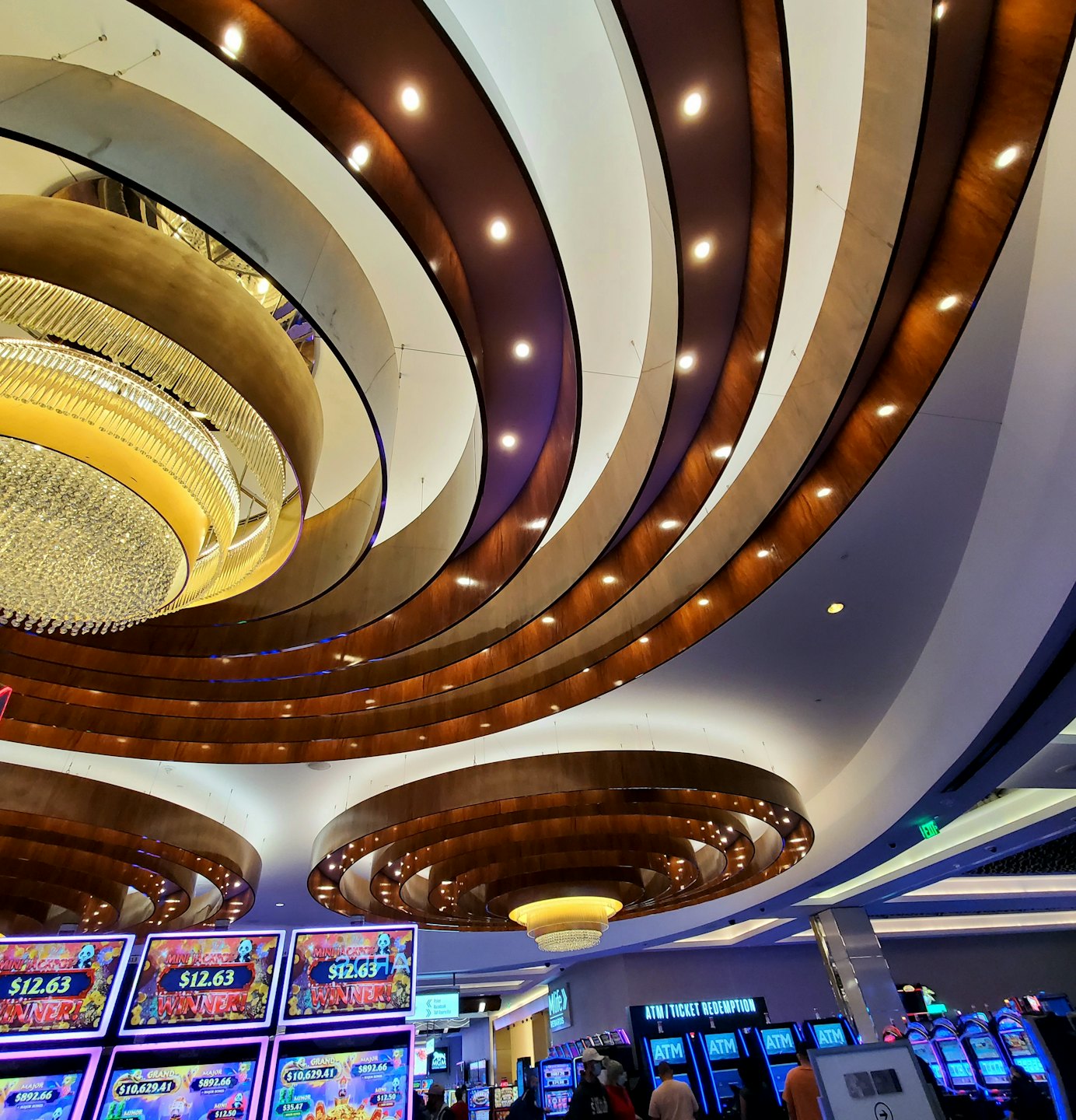 Archi ornati sul soffitto sopra file di slot machine illuminate.