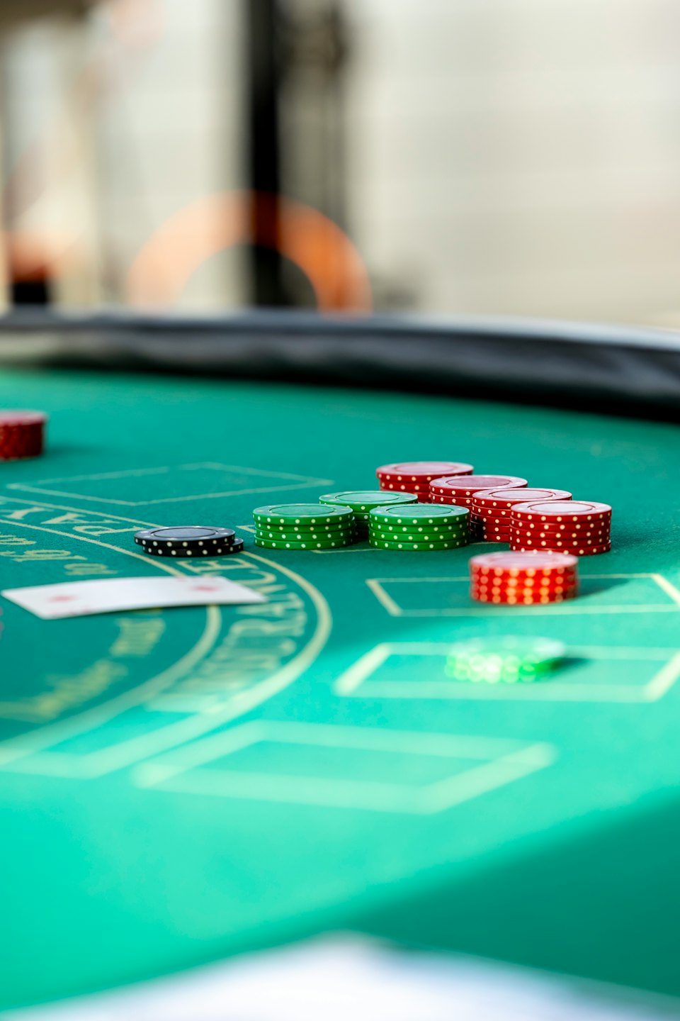 Pila di fiches da poker e una carta da gioco su un tavolo di feltro.