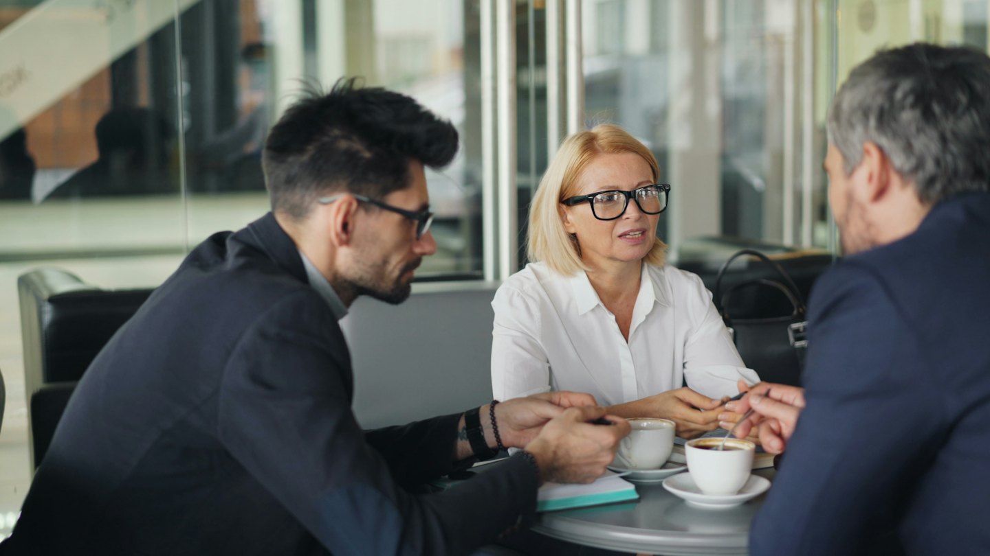Professionisti aziendali che discutono idee a un tavolo con caffè.