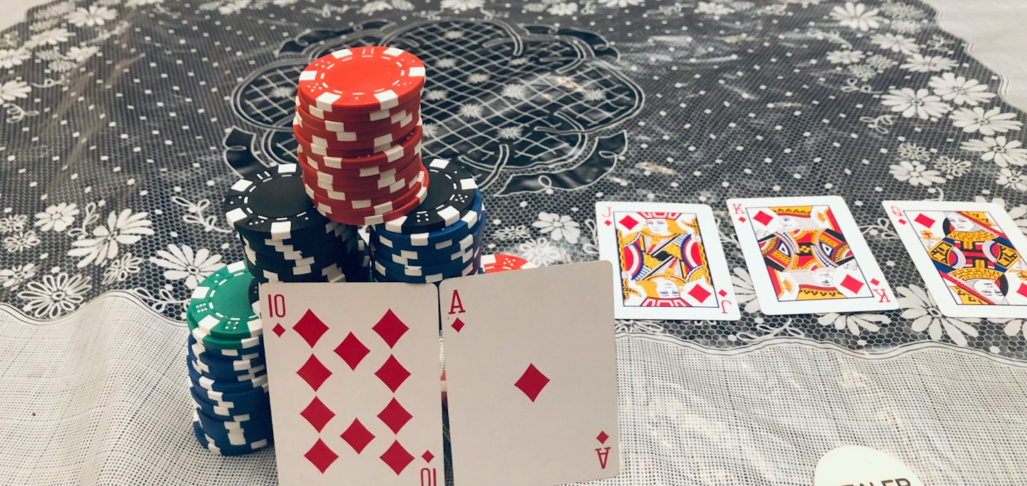 Gettoni da poker e carte disposti su una tovaglia fantasia.