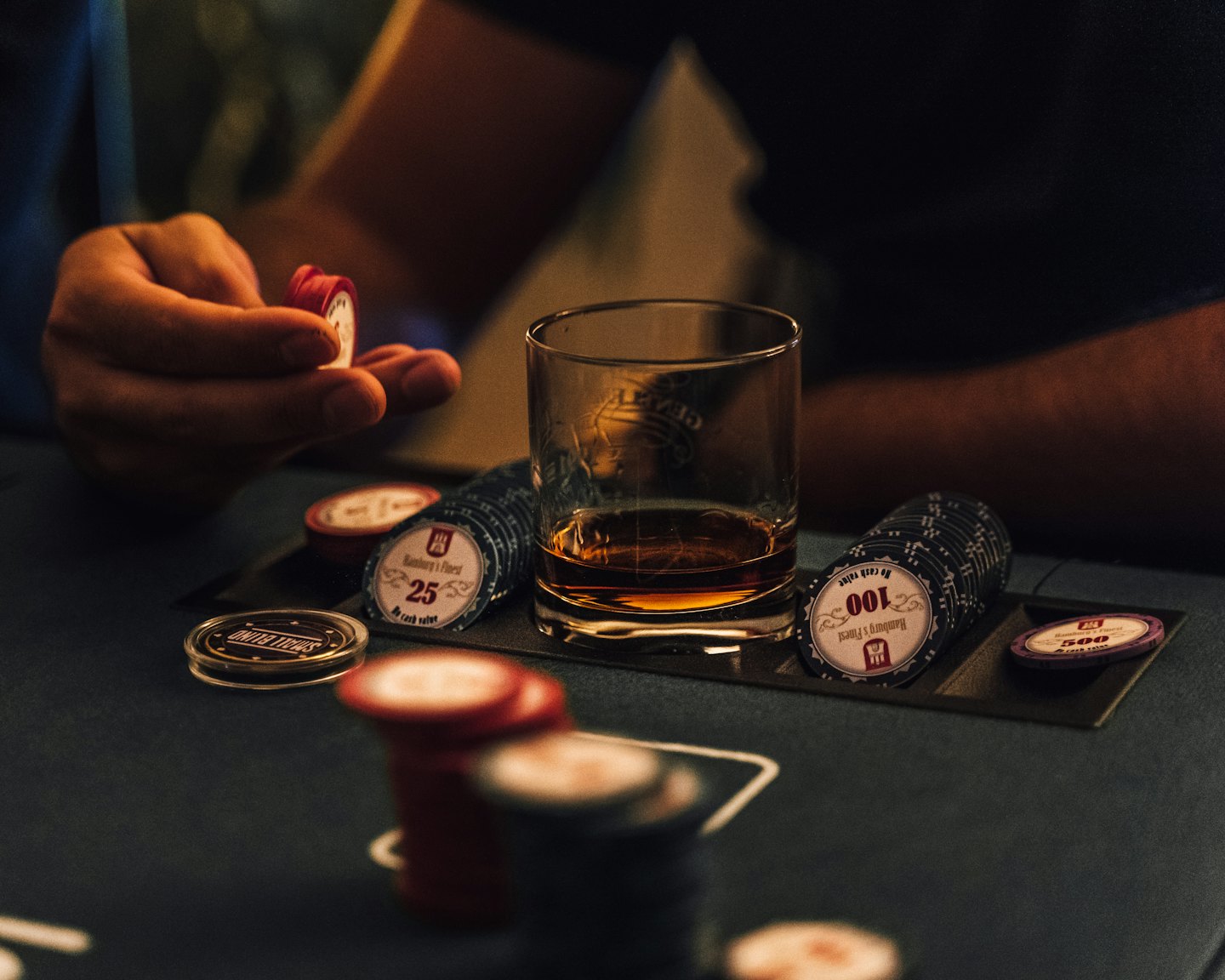Mani che tengono fiches da poker su un tavolo da gioco.
